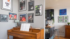 A living room with a piano, framed movie posters, a bar area, and a kitchen. - Sun Spalato Art (Split)