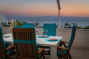 A table set for two with chairs, candles, and a view of the sea at sunset. - Sun Splato Space (Split)