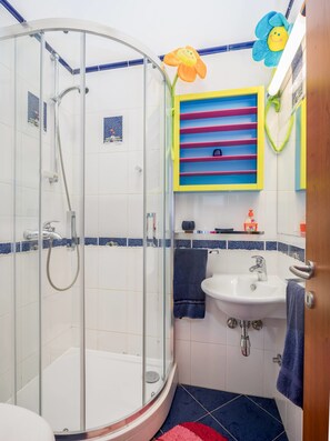 A bathroom with a glass-enclosed shower, a sink, and a colorful shelf. - Sun Splato Space (Split)