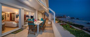 A balcony with a dining table and chairs, overlooking a beach and cityscape. - Sun Splato Space (Split)