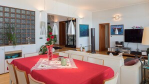 Amplia sala de estar con una mesa de comedor preparada para cuatro personas, un sofá, un televisor y una chimenea.