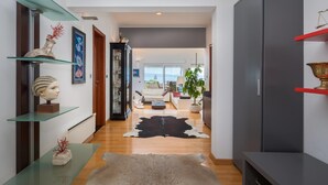 Una sala de estar moderna con una mesa de centro de vidrio, un tapete de cuero y un armario gris.