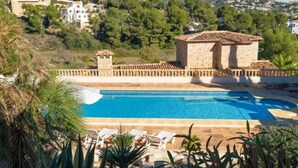 A pool area with a stone building, surrounded by greenery and overlooking a hillside. - Sunshine by Interhome (Moraira)