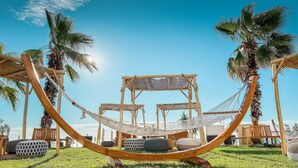 Un hamac est installé entre deux structures en bois, avec un ciel bleu clair en arrière-plan.