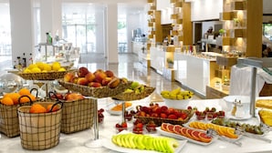 Un buffet proposant une variété de fruits et de légumes, notamment des pommes, des oranges et des bananes.