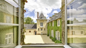 A courtyard with a central building, surrounded by walls with climbing plants. - Château de la Villedubois (Mordelles)