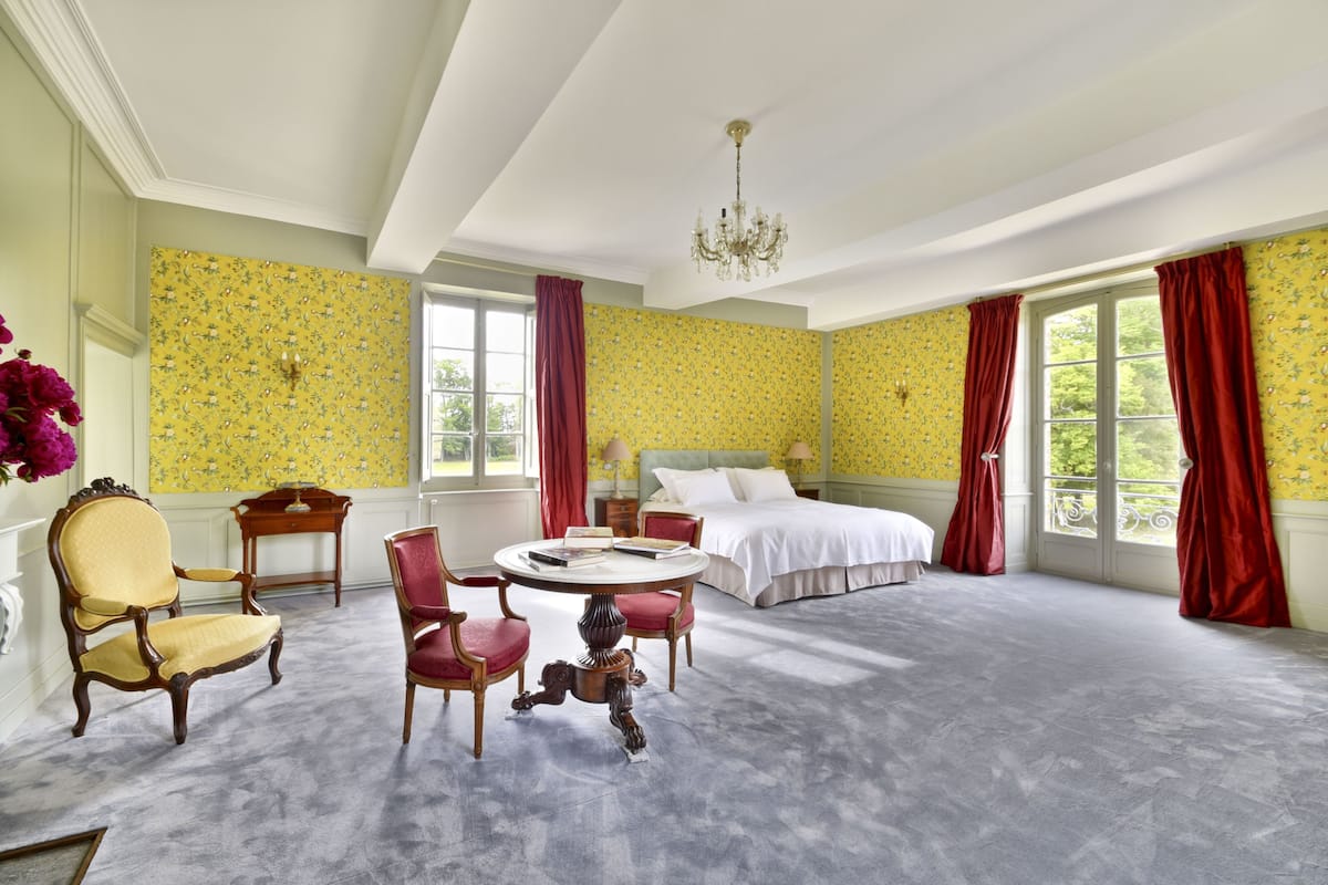 Ein geräumiges Schlafzimmer mit einem großen Bett, einem runden Tisch mit Stühlen und einer Chandelüster.