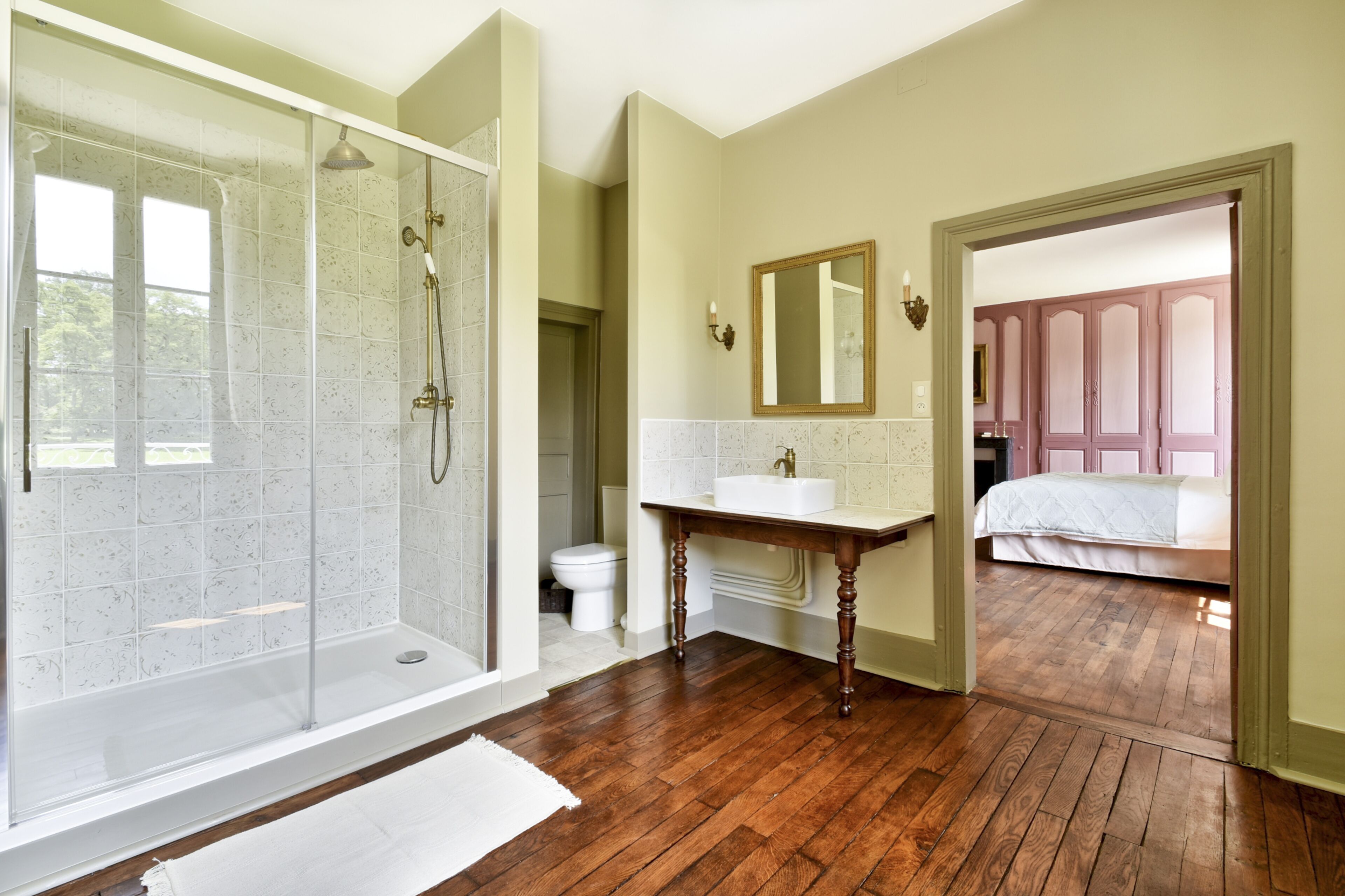 A bathroom with a glass-enclosed shower, a sink, and a mirror.