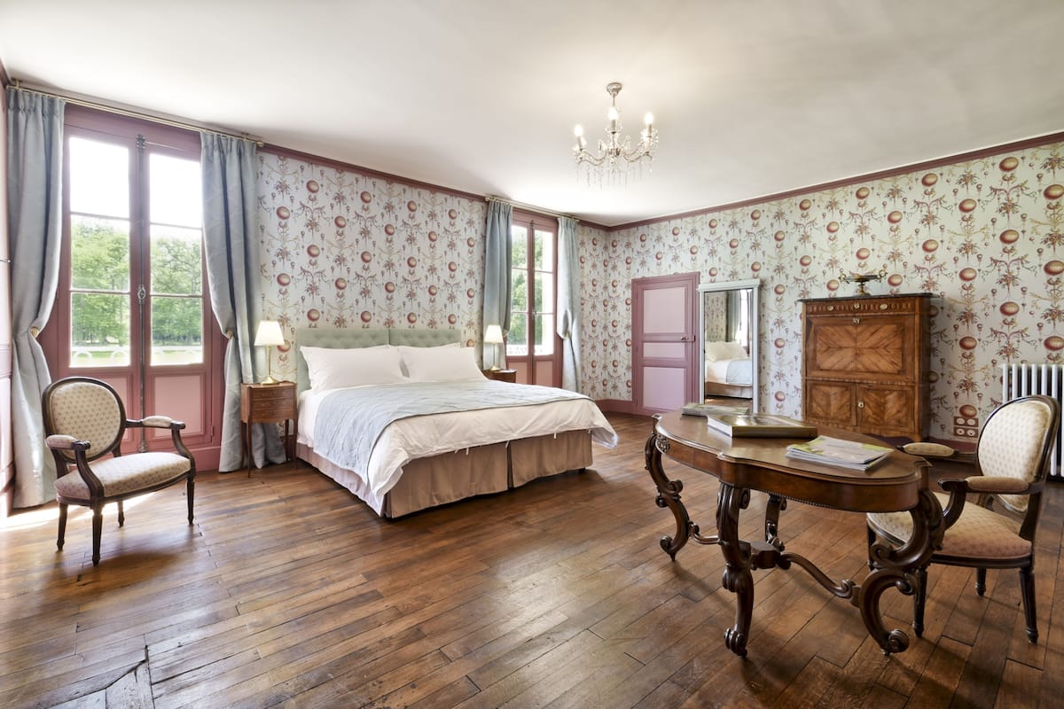 Ein Schlafzimmer mit einem großen Bett, einem hölzernen Schminktisch, einem Tisch und einem Stuhl.