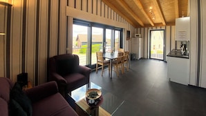 A modern living room with a sofa, a glass coffee table, and a view of the outside. - Quiet vacation apartment by the pond with a unique view Pets allowed (Schmidt)