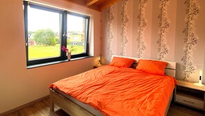 A bedroom with a large bed, a window with a view of a garden, and a wooden ceiling. - Quiet vacation apartment by the pond with a unique view Pets allowed (Schmidt)
