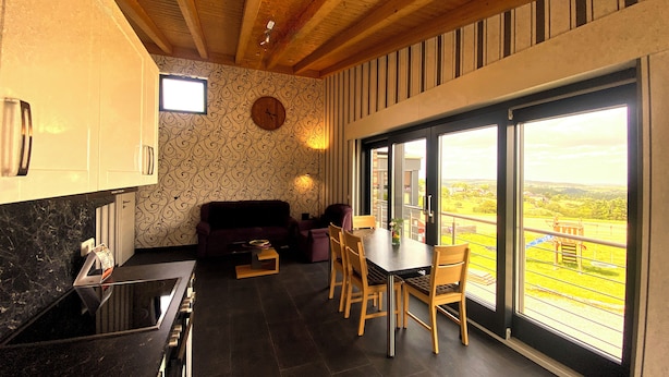 A modern kitchen with dark tiles, a wooden ceiling, and a dining area with a view. - Quiet vacation apartment by the pond with a unique view Pets allowed (Schmidt)