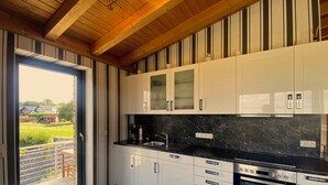 A modern kitchen with white cabinets, a black countertop, and a built-in oven. - Quiet vacation apartment by the pond with a unique view Pets allowed (Schmidt)