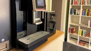 A coffee machine with a digital display, a bookshelf with books, and a door in a room. - Quiet vacation apartment by the pond with a unique view Pets allowed (Schmidt)