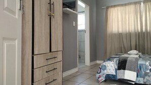 Een slaapkamer met een bed, een kledingkast en een badkamer, zichtbaar door een geopende deur.