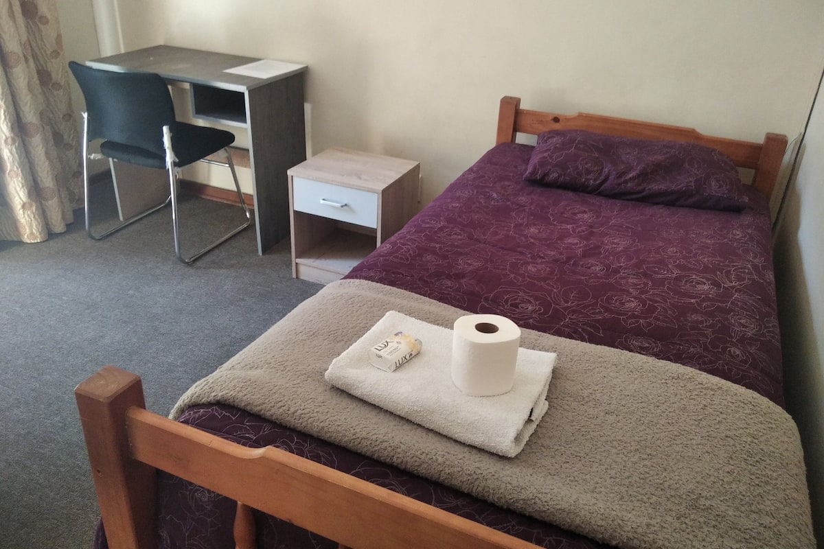 Un dormitorio con una cama, un escritorio y una silla.