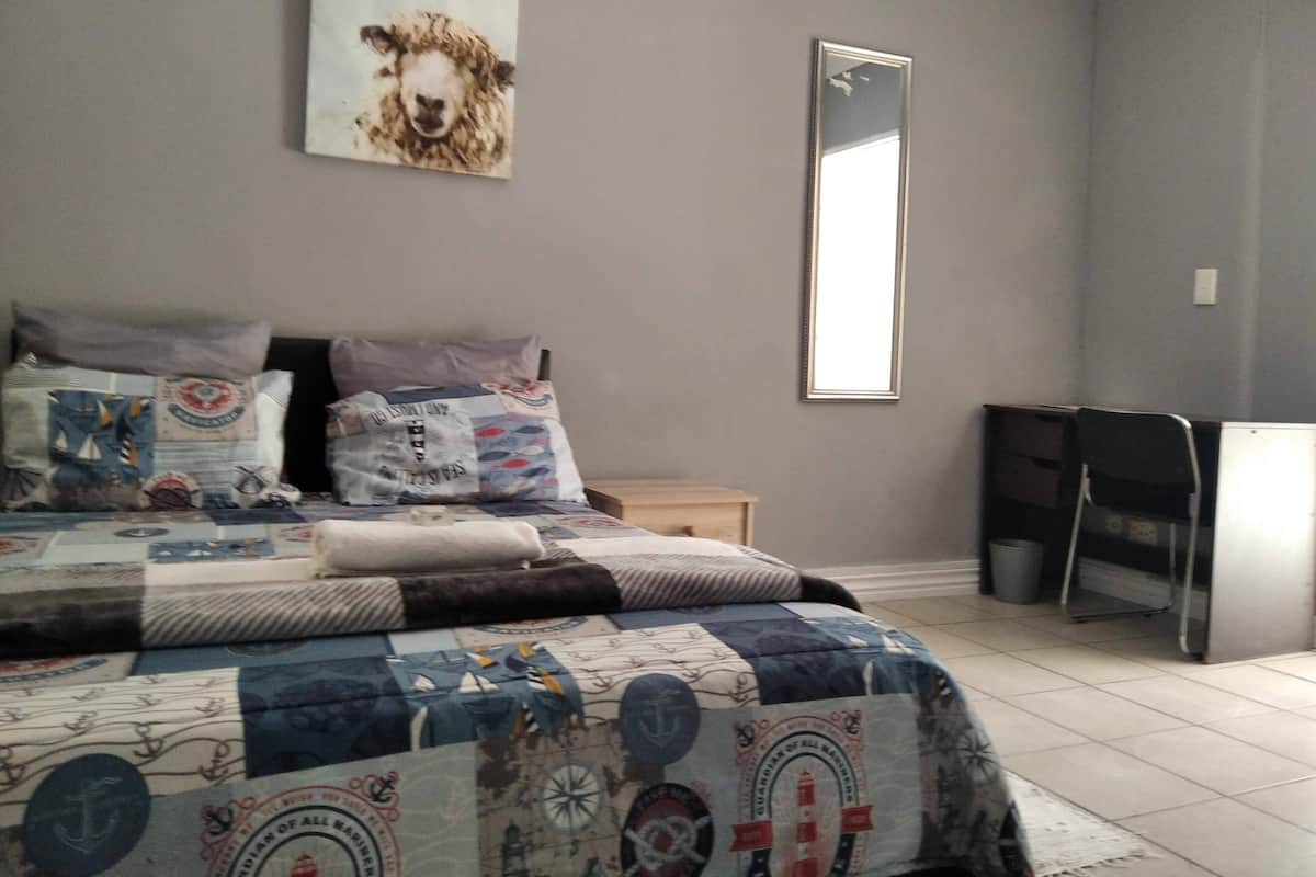 Un dormitorio con cama, almohadas, escritorio y una silla.