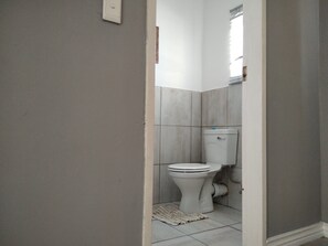 Ein Badezimmer mit Toilette, geflieste Wände und einem kleinen Teppichboden.