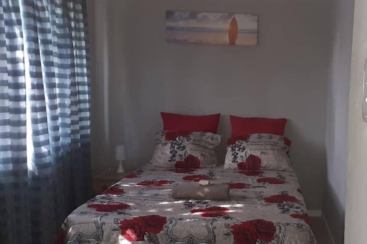 Un dormitorio con cama, almohadas rojas y colcha estampada.