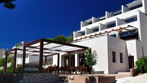 Un espacio moderno para sentarse al aire libre con pared de piedra y pérgola de madera, con vista a la calle.