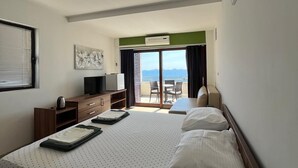 Habitación de hotel con una cama grande, un escritorio, televisión y balcón con vistas.