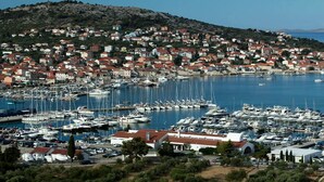 Un puerto deportivo con numerosas embarcaciones amarradas, rodeado por un pueblo costero con edificios de tejas rojas.
