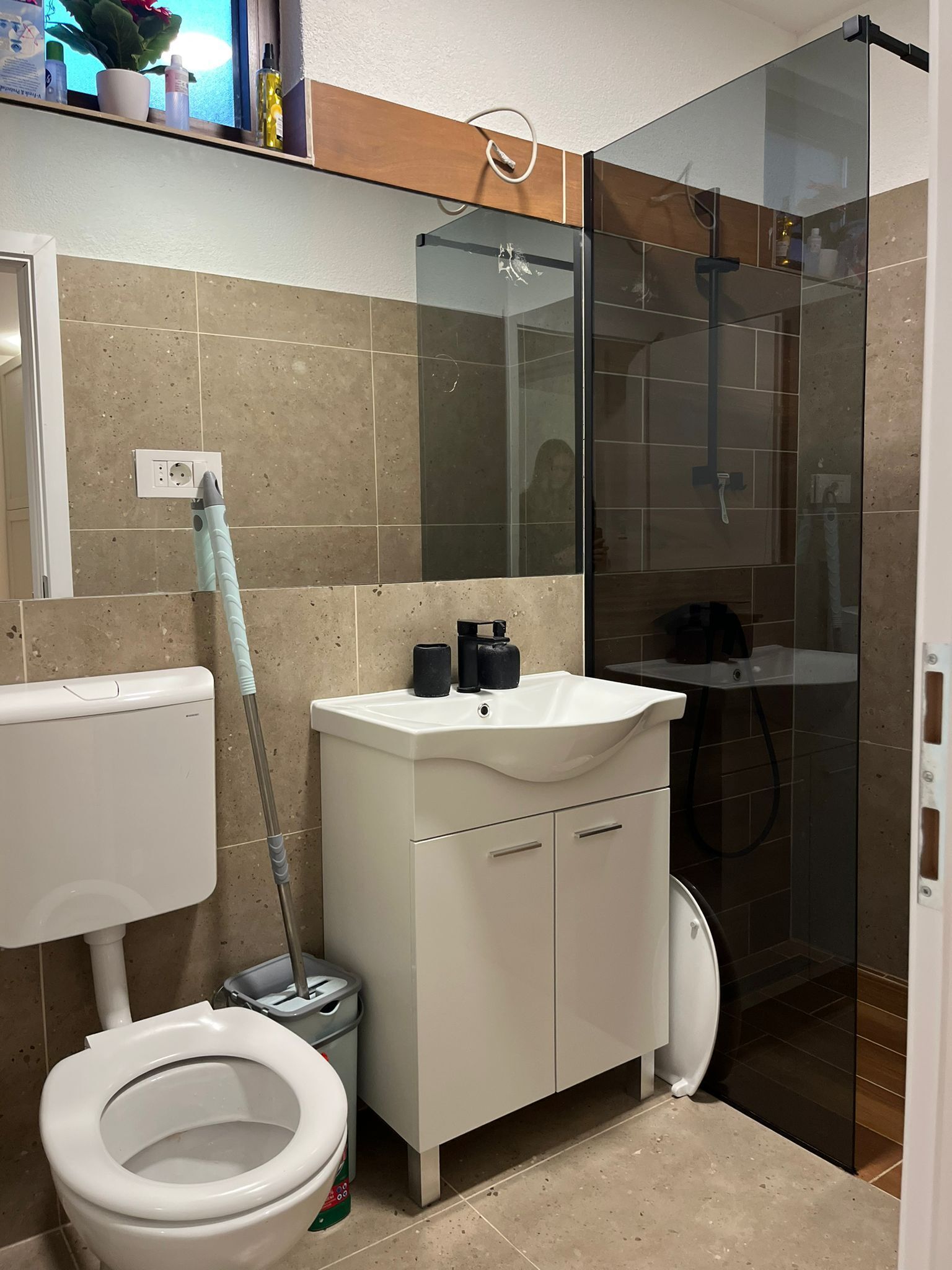 A modern bathroom with a toilet, sink, and glass shower enclosure.