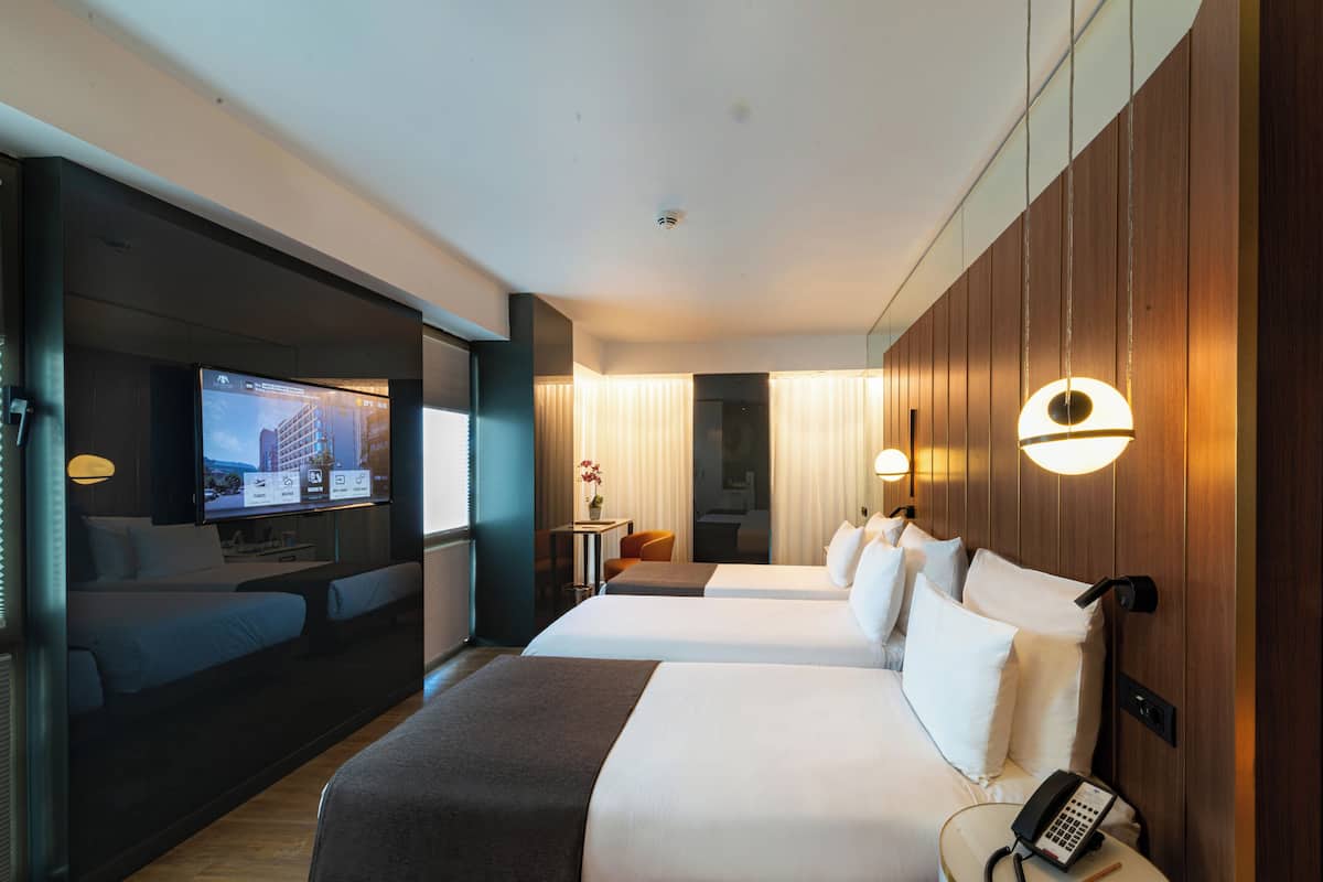 A hotel room with two beds, a TV, a desk, and a phone.