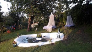 Un jardín con un estanque, un columpio y una valla.