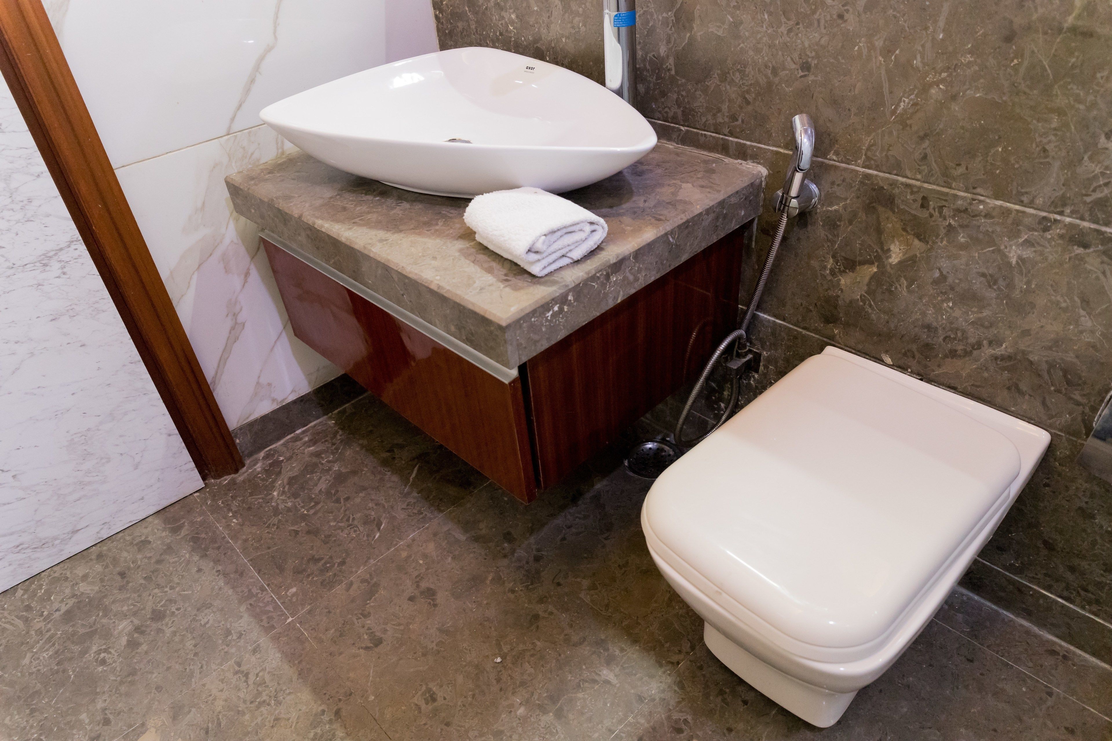 A bathroom with a white sink, a toilet, and a marble-tiled floor.