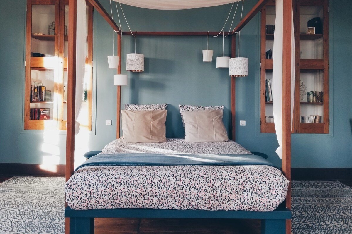A four-poster bed with a canopy, two bedside tables, and a built-in bookshelf on either side.