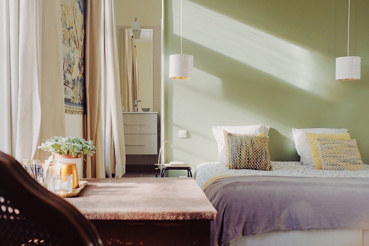 A bedroom with a bed, bedside table, and a window with curtains.