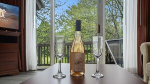 Una botella de vino Chantal y dos copas sobre una mesa, con un televisor al fondo.