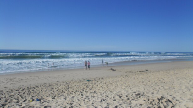 Uma praia com pessoas caminhando e brincando.