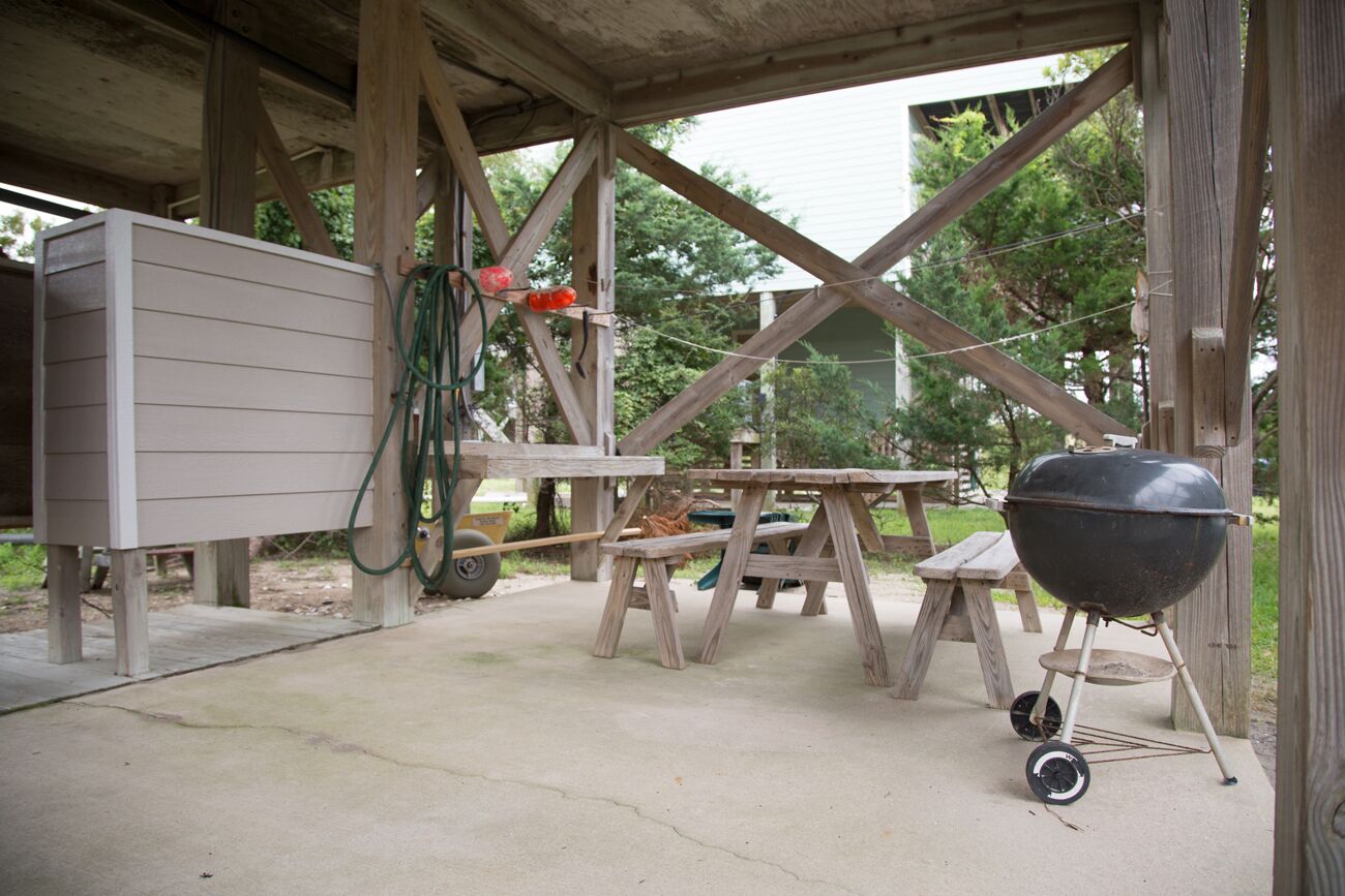 An outdoor patio with a wooden table and a barbecue grill.