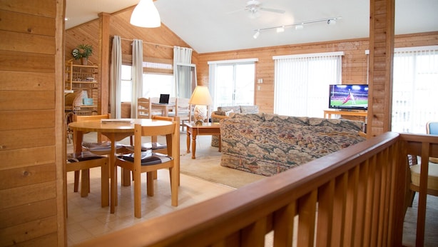 Interior acogedor de una cabaña con comedor, sofá y televisor.