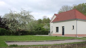 A single-story building with a red-tiled roof, a small front porch, and a paved driveway. - La Ferme d'Antan (Mons-Boubert)