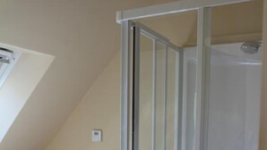 A room with a glass shower enclosure, a white radiator, and a stack of folded towels. - La Ferme d'Antan (Mons-Boubert)