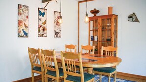 A dining area with a wooden table and chairs, a patterned rug, and wall art.