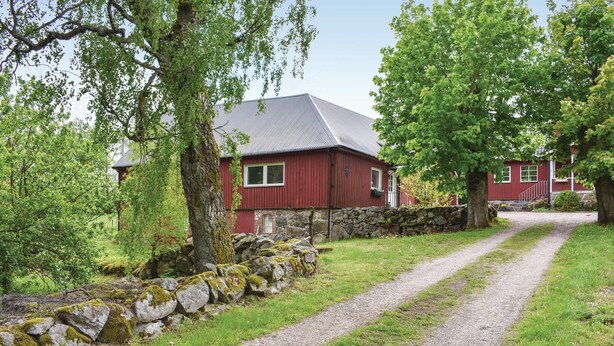 A red house with a stone wall and a gravel path leading to it.