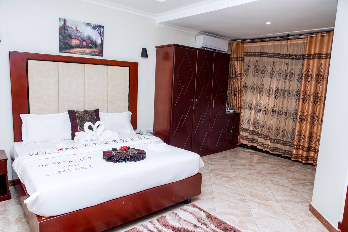 A hotel room with a large bed, a wardrobe, and a curtain.