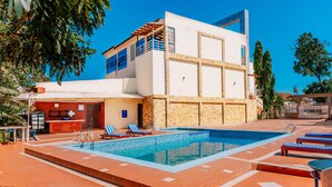 Ein modernes Gebäude mit Swimmingpool, blauen Liegestühlen und einer Bar.