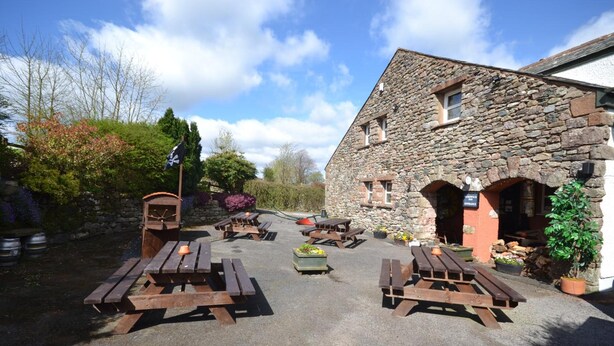 A stone building with outdoor seating and a flag. - The Herdwick Inn (Penrith)