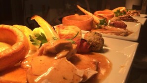 A variety of dishes including a Yorkshire pudding, a piece of meat with gravy, and a sausage roll. - The Herdwick Inn (Penrith)