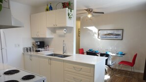 A modern kitchen with a white stove, a sink, and a dining area with a table and chairs.