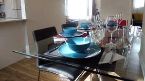 A dining area with a glass table set for four, blue bowls, and wine glasses.