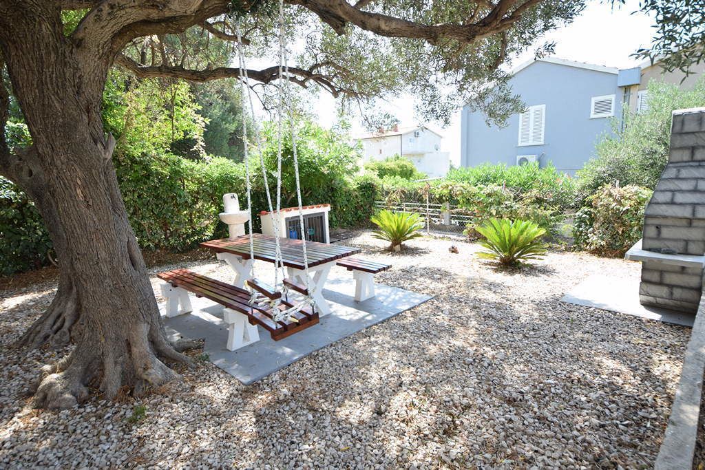 Ein Garten mit Schaukel, Bank und einem kleinen Tisch.