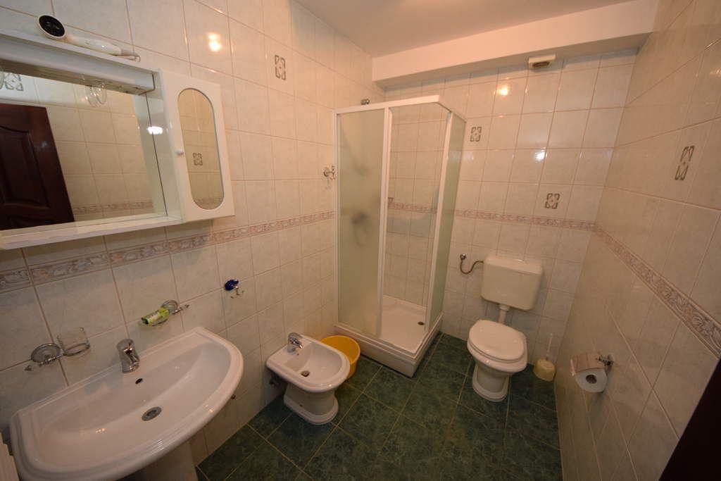 A bathroom with a sink, bidet, toilet, and a glass-enclosed shower.
