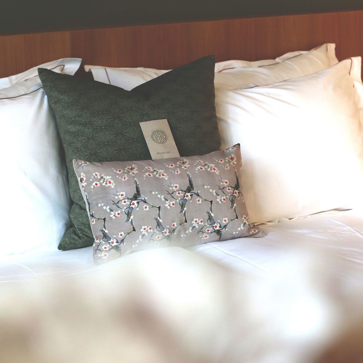 A bed with two pillows, one plain and one with a floral pattern.