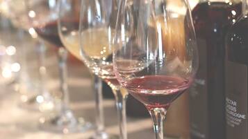 Una hilera de copas de vino sobre una mesa con botellas detrás.